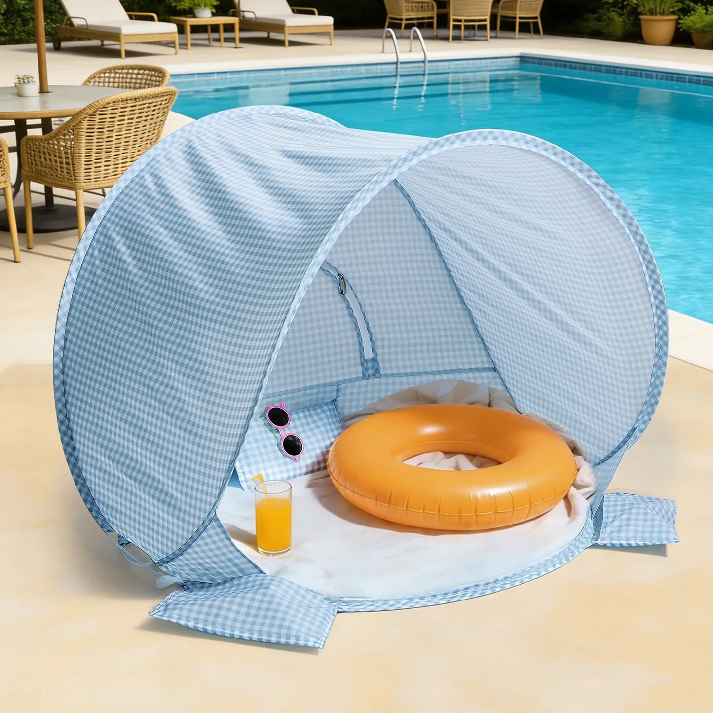 The Tiny Land® One-Stop Beach Toy & Tent Set in light blue gingham shelters an orange swim ring, sunglasses, and a glass of orange juice on a white towel by the pool, with a wicker chair and table nearby.|Light Blue Gingham