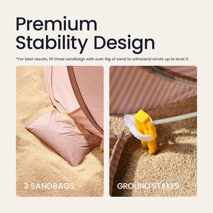 Two close-up images show the Tiny Land® One-Stop Beach Toy & Tent Set – Blush Pink with UV protection, secured by sandbags and yellow stakes. Text highlights its Premium Stability Design and tips for anchoring in windy conditions.|Blush Pink